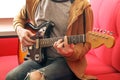 Casually dressed young man with guitar playing songs in the room at home. Online guitar lessons concept. Male guitarist practicing