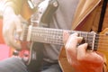 Casually dressed young man with guitar playing songs in the room at home. Online guitar lessons concept. Male guitarist practicing