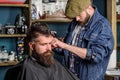 Hipster lifestyle concept. Hipster client getting haircut. Barber with hair clipper work on hairstyle for bearded