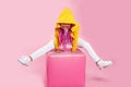 Little girl child in white jeans, colored clothes sitting with raised legs on a chair in the studio, on pink background Royalty Free Stock Photo