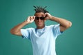 Hipster look. Stylish young man with dreads hairstyle, sunglasses and casual clothes against green studio background Royalty Free Stock Photo