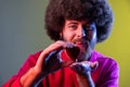 Hipster man with Afro hairstyle holding red toy heart, showing his fondness and devotion, romance.