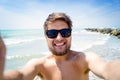 Hipster man on beach, smiling, taking selfie, sunny summer Royalty Free Stock Photo