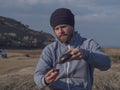 Hipster man with a beard and in a knitted hat pours tea from a clay teapot into a bowl. chinese tea ceremony