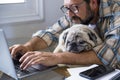 Hipster man with beard work at home on laptop computer and internet connection with his friend old dog Royalty Free Stock Photo