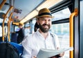 Hipster man on a bus in the city, travelling to work and reading newspapers.