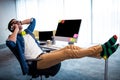 Hipster man calling with smartphone while relaxing at computer desk Royalty Free Stock Photo