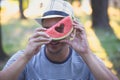 Hipster man hold a piece of watermelon and looks through a sign