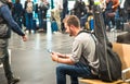 Hipster man at international airport using mobile smart phone Royalty Free Stock Photo