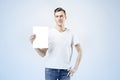 Hipster man model standing with blank sheet in hands, isolated on white background, wearing jeans and t-shirt. Royalty Free Stock Photo