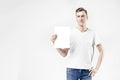 Hipster man model standing with blank sheet in hands, isolated on white background, wearing jeans and t-shirt. Space for design la Royalty Free Stock Photo