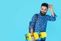 Hipster man over colorful blue background holding yellow skateboard