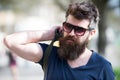 Hipster man with stylish beard and mustache walking in city. Closeup portrait of handsome young man in trendy eyewear Royalty Free Stock Photo