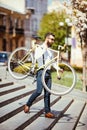 Hipster man in sunglasses carrying on his shoulder bike on street stairs. A young handsome man with beard holding bike on his righ Royalty Free Stock Photo