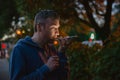 Hipster man talking on a mobile phone at night in the city against the background of bokeh lights. Royalty Free Stock Photo