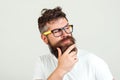 Hipster man thinking, touching his beard. Bearded guy in glasses thoughtful, on white background. Handsome bearded guy with Royalty Free Stock Photo