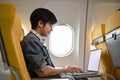 Hipster Asian male traveler passenger using laptop during the flight. remote working concept Royalty Free Stock Photo