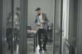 Hipster in modern office with glass walls. Bearded man seen in room door. Confident businessman in casual suit at Royalty Free Stock Photo
