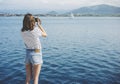 Hipster photograph on vintage camera or technology, mock up. Girl using vintage camerae on blue sea and yacht background close