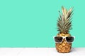 Hipster pineapple with sunglasses against a teal background