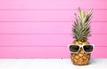 Hipster pineapple with sunglasses against pink wood