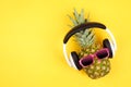 Hipster pineapple with sunglasses and headphones over a yellow background