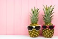 Hipster pineapples with sunglasses against pink wood