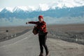 Hipster in red hitchhiking on old dusty road Royalty Free Stock Photo