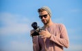 Hipster reporter taking photo. Guy photographer outdoors sky background. Handsome photographer guy retro camera. Manual