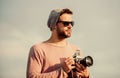 Hipster reporter taking photo. Guy photographer outdoors sky background. Photojournalist concept. Travel blogger