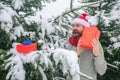 Hipster santa at Christmas tree in snowy winter forest.