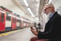 Hipster senior man chatting on his smartphone while waits for subway train - Mature man having fun with technology trends - Tech