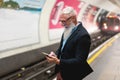 Hipster senior man chatting on his smartphone while waits for subway train - Mature man having fun with technology trends - Tech