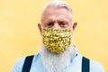 Hipster senior man wearing trendy face mask during coronavirus outbreak - Old fashion and washable eco cotton concept - Focus on