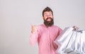 Hipster on smiling face recommends to buy. Man with beard and mustache carries bunch of shopping bags, grey background Royalty Free Stock Photo