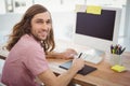 Hipster smiling while using graphics tablet at computer desk Royalty Free Stock Photo