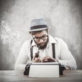 Composite image of hipster smoking pipe while working at desk Royalty Free Stock Photo