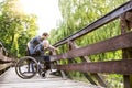 Hipster son walking with disabled father in wheelchair at park. Royalty Free Stock Photo