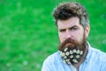 Hipster on strict face, green grass background, copy space. Man with beard and mustache enjoy spring, green meadow Royalty Free Stock Photo