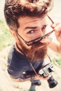 Hipster on strict face holds old fashioned camera. Tourist photographer concept. Guy shooting nature near river or pond