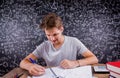 Hipster student doing his homework against a big blackboard