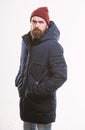 Hipster style menswear. Hipster outfit. Man bearded hipster posing confidently in warm black jacket or parka. Stylish