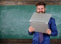 Hipster teacher wear eyeglasses and necktie bites laptop. Man hungry for knowledge. Teacher bearded man bites modern Royalty Free Stock Photo