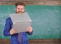 Hipster teacher wear eyeglasses and necktie bites laptop. Man hungry for knowledge. Teacher bearded man bites modern Royalty Free Stock Photo