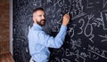 Hipster teacher writing on big blackboard with mathematical symbols Royalty Free Stock Photo