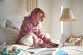 Hipster teen girl student with pink hair using laptop online learning in bed.