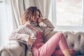 Teenage girl in sweater and jumpsuit on a couch Royalty Free Stock Photo