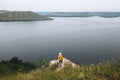 Hipster teenager standing on top of rock mountain and looking on river, view from back. Young stylish guy exploring and traveling Royalty Free Stock Photo