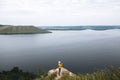 Hipster teenager in yellow pullover standing on top of rock mountain and looking on river, view from back. Young stylish guy Royalty Free Stock Photo