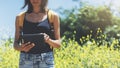 Hipster texting message on tablet or technology, mock up of blank screen. Girl using computer on yellow flowers background close Royalty Free Stock Photo